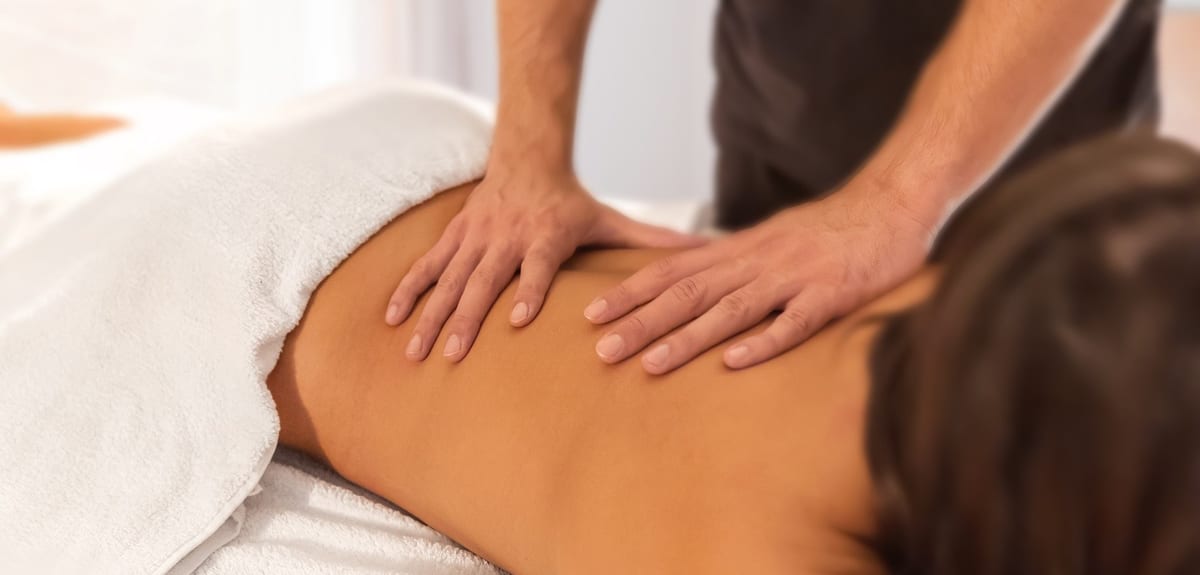 A therapist's hands working along a patient's back